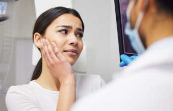 A dentist showing digital imaging to a young woman with severe dental pain